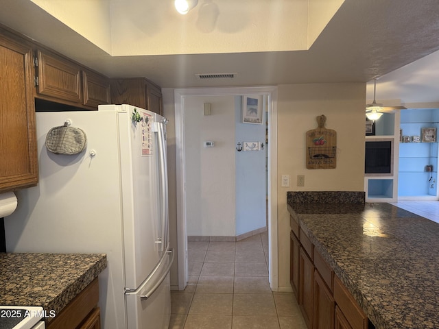 kitchen with visible vents, ceiling fan, light tile patterned floors, freestanding refrigerator, and stove