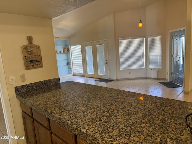 interior space featuring lofted ceiling, light tile patterned flooring, baseboards, and plenty of natural light