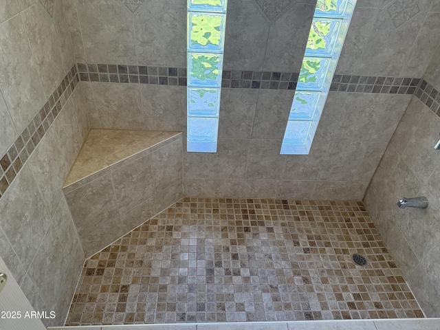 bathroom featuring a tile shower and a healthy amount of sunlight