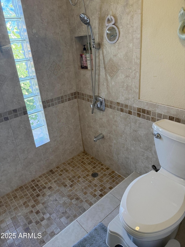 full bath featuring a wealth of natural light, tile patterned floors, a tile shower, and toilet