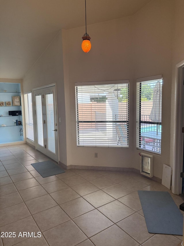 doorway featuring baseboards, high vaulted ceiling, and light tile patterned flooring