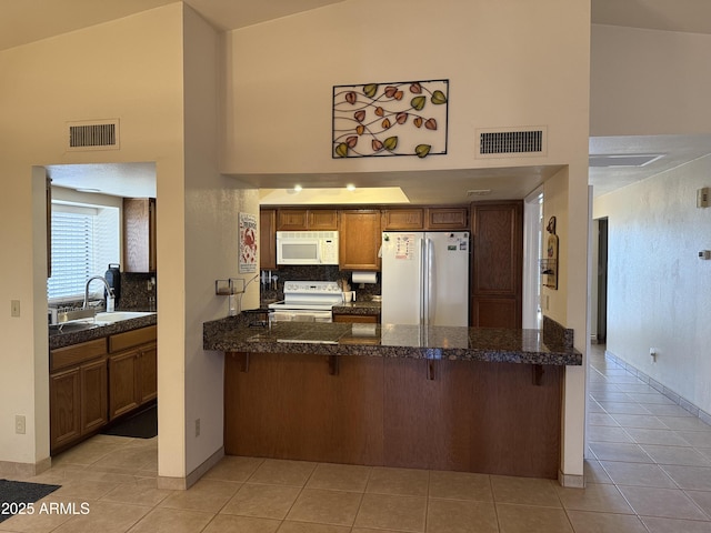 kitchen featuring visible vents, white appliances, and high vaulted ceiling