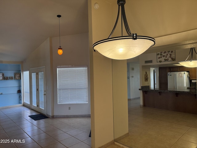 kitchen with visible vents, decorative light fixtures, light tile patterned floors, freestanding refrigerator, and high vaulted ceiling