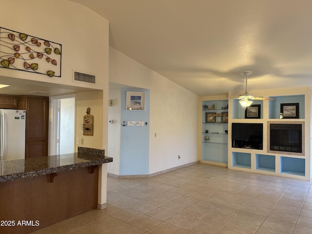 unfurnished living room featuring built in shelves, baseboards, visible vents, light tile patterned flooring, and ceiling fan