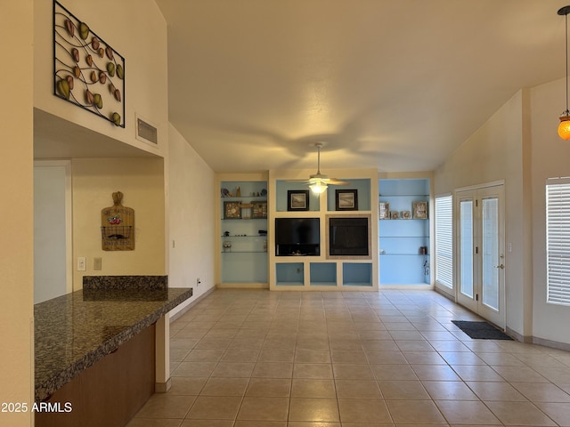 unfurnished living room featuring built in shelves, light tile patterned flooring, visible vents, and ceiling fan