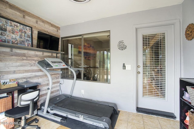 exercise room with tile patterned floors and wood walls