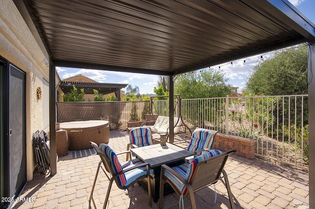 view of patio / terrace with a fenced backyard, outdoor dining space, and a hot tub