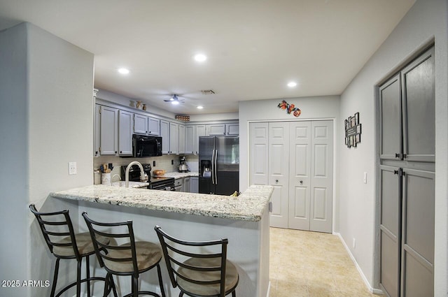 kitchen with black microwave, range with electric cooktop, a peninsula, recessed lighting, and refrigerator with ice dispenser