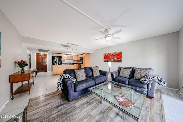 living area with visible vents, baseboards, light tile patterned floors, rail lighting, and a ceiling fan