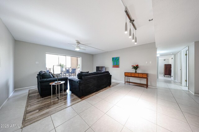 living area featuring light tile patterned flooring, track lighting, baseboards, and a ceiling fan