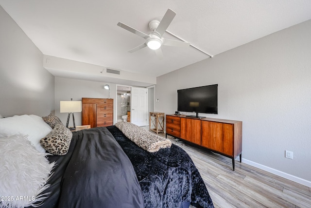 bedroom with a ceiling fan, visible vents, baseboards, light wood finished floors, and connected bathroom