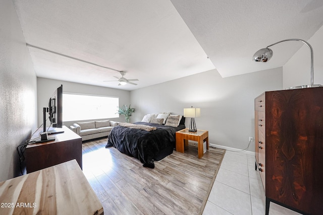 bedroom with light wood-style flooring, a textured ceiling, baseboards, and ceiling fan