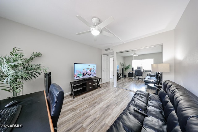 living area featuring visible vents, baseboards, light wood-style floors, and a ceiling fan