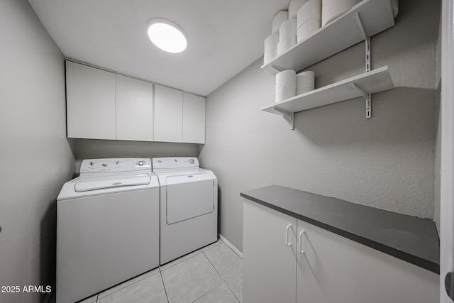 washroom featuring washing machine and clothes dryer, cabinet space, and light tile patterned flooring