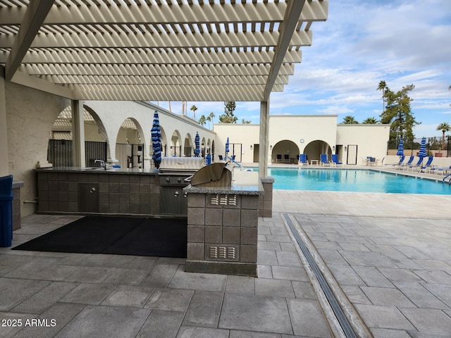 pool featuring area for grilling, an outdoor kitchen, a pergola, a patio, and a sink