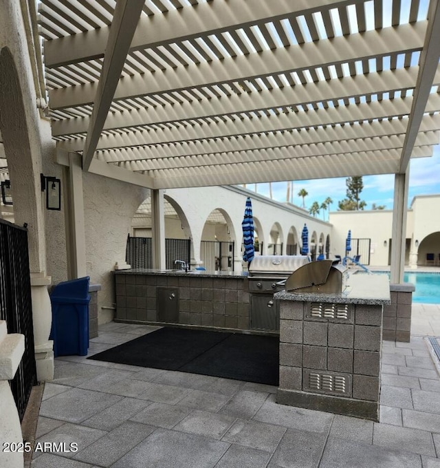 view of patio / terrace featuring a sink, a pergola, and an outdoor kitchen