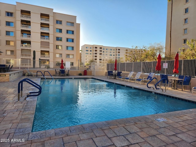 community pool with a patio and fence