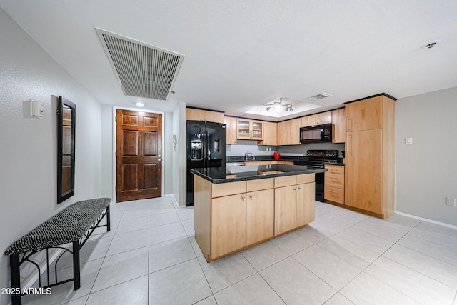 kitchen with visible vents, black appliances, light brown cabinetry, a center island, and light tile patterned floors