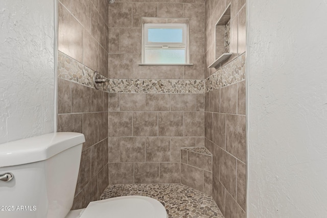 bathroom featuring toilet and a tile shower