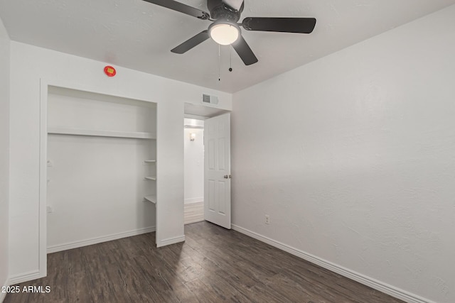 unfurnished bedroom with dark wood-type flooring, ceiling fan, and a closet