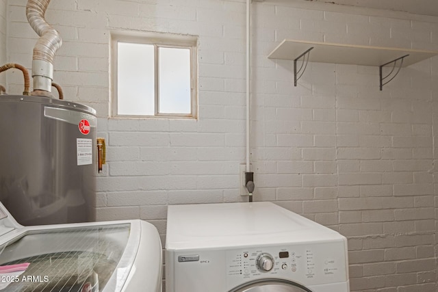 laundry area featuring water heater, brick wall, and independent washer and dryer