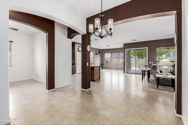 interior space with arched walkways, baseboards, an inviting chandelier, and light tile patterned flooring