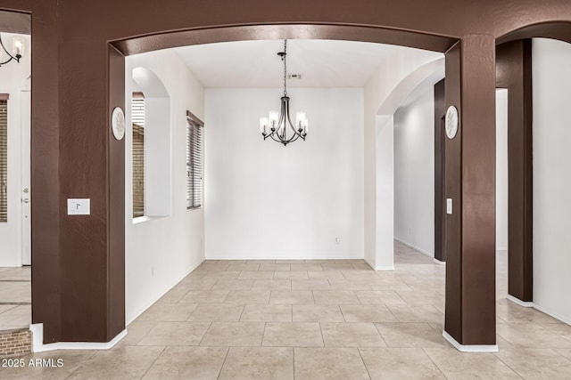unfurnished dining area featuring arched walkways, light tile patterned floors, and an inviting chandelier