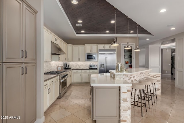 17673 E Bronco Dr, Queen Creek, AZ 85142 - kitchen with tasteful backsplash, built in appliances, cream cabinets, a raised ceiling, and under cabinet range hood