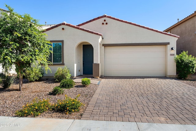 5429 W Chuck Box Rd, Laveen, AZ 85339 - mediterranean / spanish-style house featuring stucco siding, decorative driveway, an attached garage, and a tiled roof