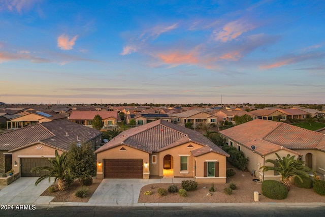 view of front of home featuring stucco siding, a tile roof, a residential view, concrete driveway, and an attached garage