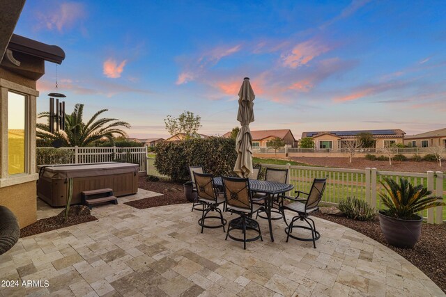 patio terrace at dusk with a hot tub and a lawn