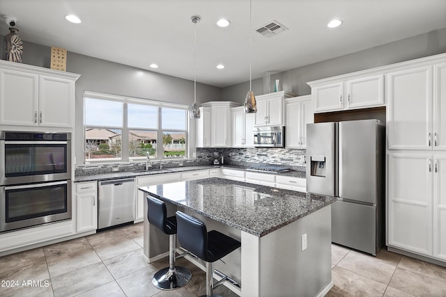 kitchen featuring visible vents, backsplash, a kitchen island, stainless steel appliances, and white cabinetry