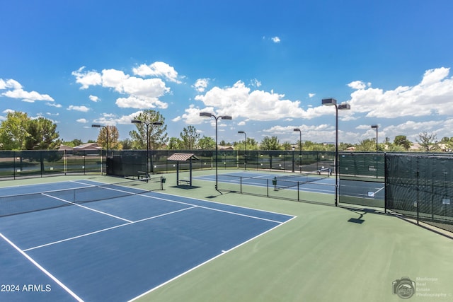 view of tennis court with community basketball court and fence