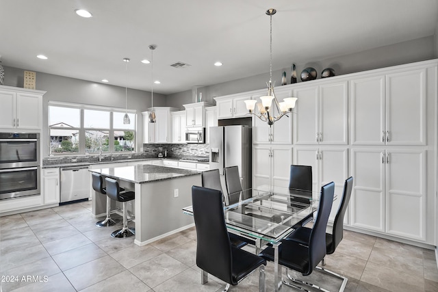 kitchen featuring a center island, stainless steel appliances, white cabinetry, decorative backsplash, and visible vents