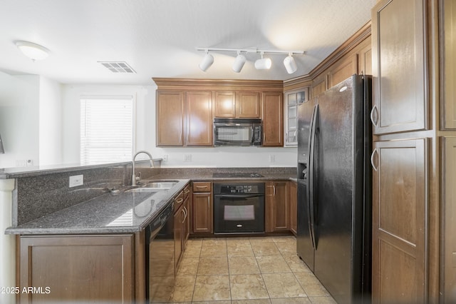 5749 S 21st Ter, Phoenix, AZ 85040 - kitchen with black appliances, a sink, brown cabinetry, dark stone counters, and a peninsula