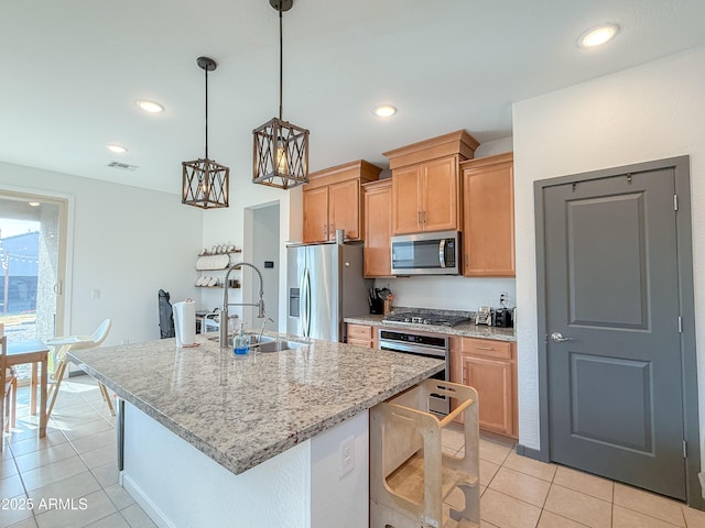 kitchen featuring light stone counters, stainless steel appliances, pendant lighting, light tile patterned floors, and an island with sink