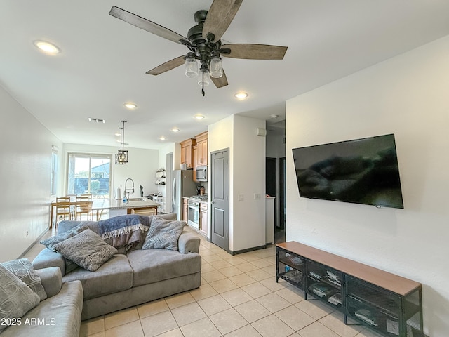 tiled living room featuring ceiling fan and sink