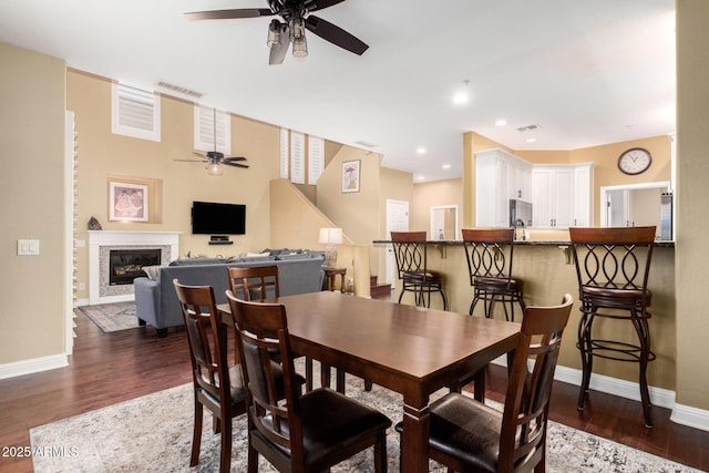 dining area with a glass covered fireplace, visible vents, and dark wood-style floors