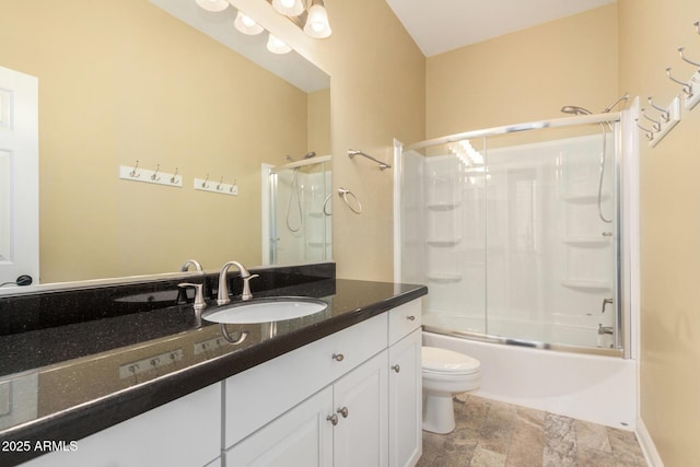 bathroom featuring vanity, stone finish flooring, toilet, and enclosed tub / shower combo