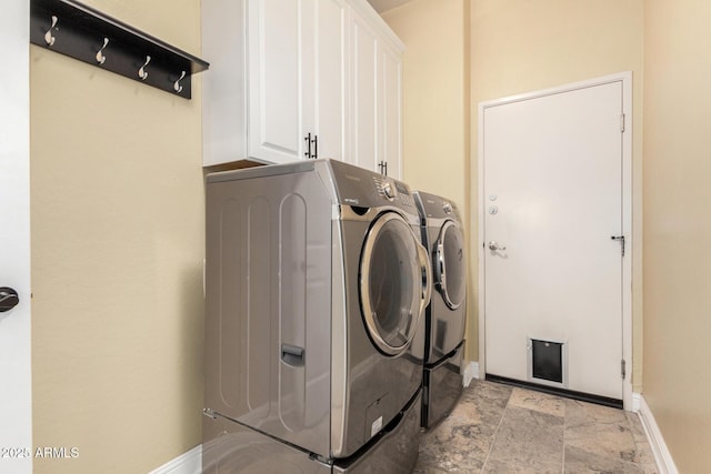 laundry room with washer and dryer, cabinet space, baseboards, and stone finish flooring