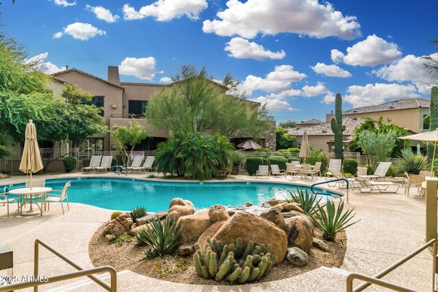 pool with a patio area and fence