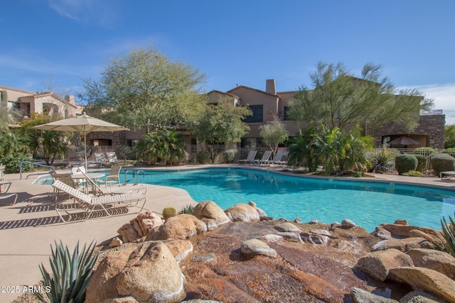 community pool with fence and a patio area