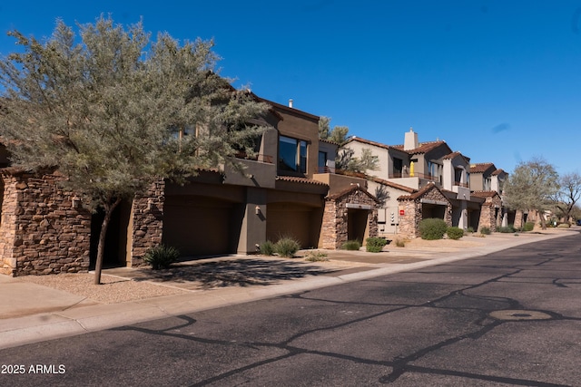 view of front of property featuring stucco siding, a tile roof, stone siding, a residential view, and a chimney