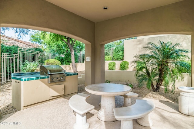 view of patio with outdoor dining space, exterior kitchen, a fenced backyard, and a grill