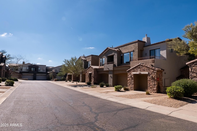 view of front of home with stucco siding, stone siding, a residential view, a balcony, and a chimney