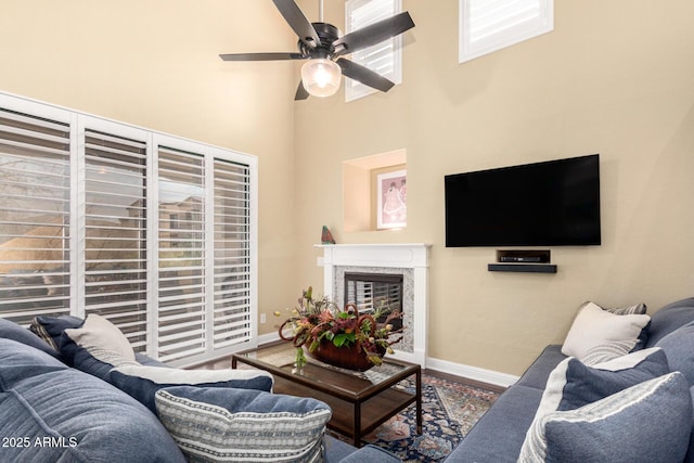 living area with ceiling fan, a fireplace, baseboards, and wood finished floors