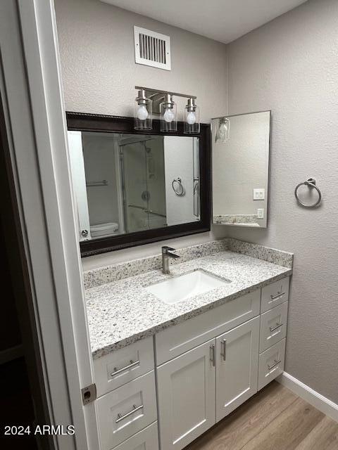 bathroom with hardwood / wood-style flooring, vanity, and a shower