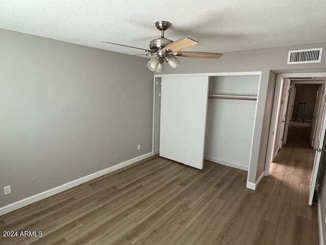 unfurnished bedroom with ceiling fan, dark hardwood / wood-style floors, a textured ceiling, and a closet