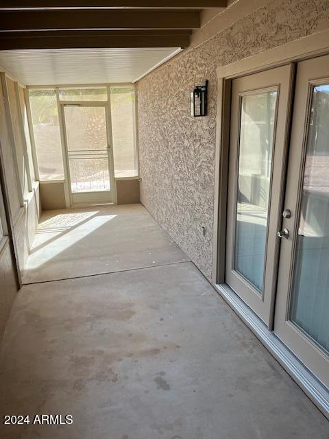 unfurnished sunroom with beam ceiling