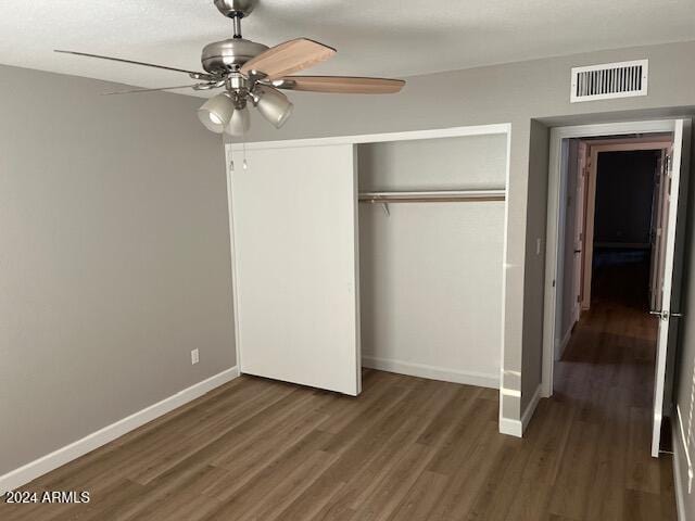 unfurnished bedroom with ceiling fan, dark hardwood / wood-style floors, and a closet